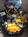 Festive birthday gift arrangement featuring a "Happy Birthday" balloon, yellow roses, Ferrero Rocher chocolates, a mug, and personalised birthday cards.