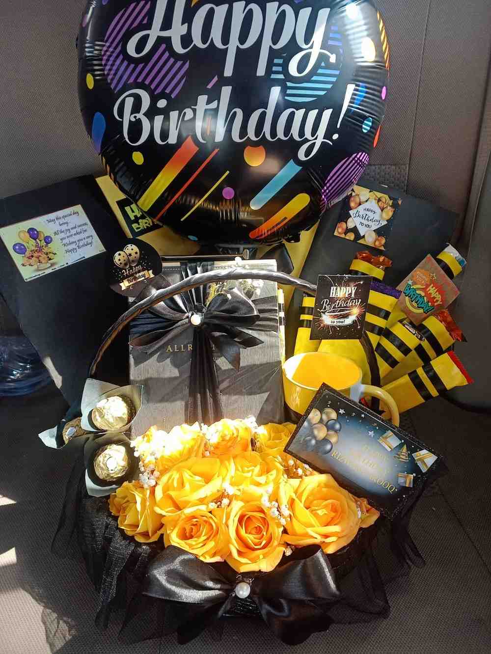 Festive birthday gift arrangement featuring a "Happy Birthday" balloon, yellow roses, Ferrero Rocher chocolates, a mug, and personalised birthday cards.
